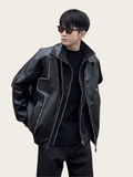 Person wearing a black leather jacket with reflective accents on a plain background