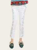 White jeans with floral embroidery worn by a person on a white background