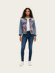 Woman wearing a floral denim jacket and blue jeans on a white background