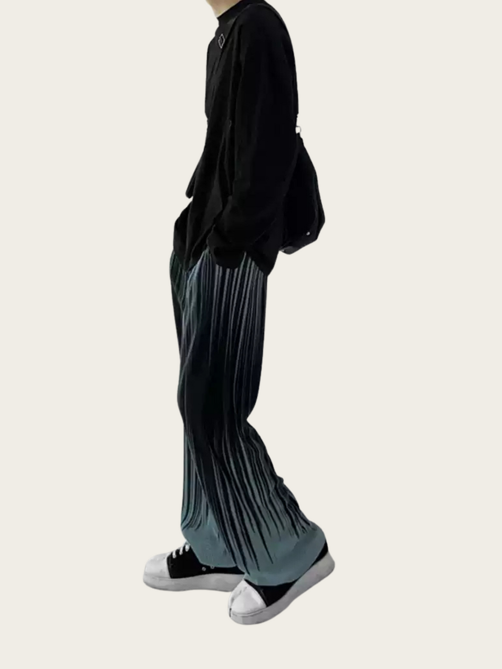 Person wearing black top and pleated gray pants on a white background