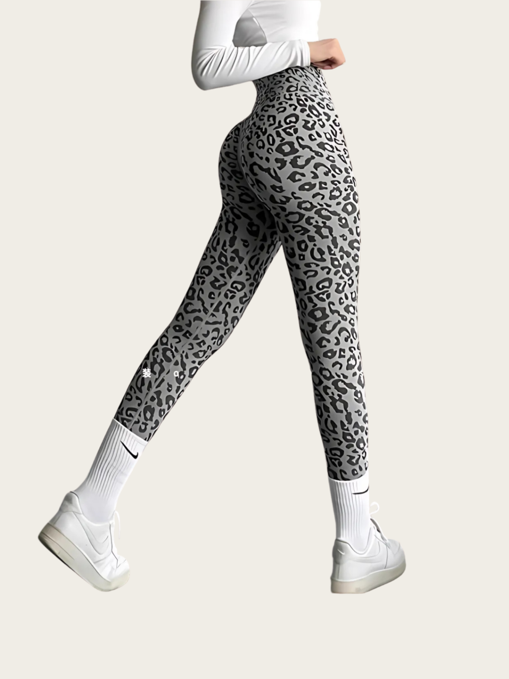 Person wearing gray leopard print leggings on a white background