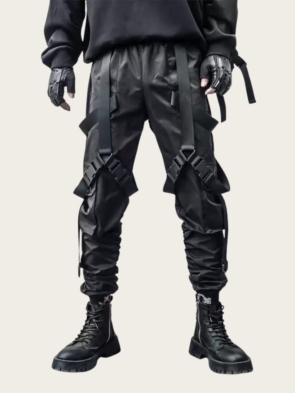 Person wearing black tactical pants with multiple straps on a light gray background