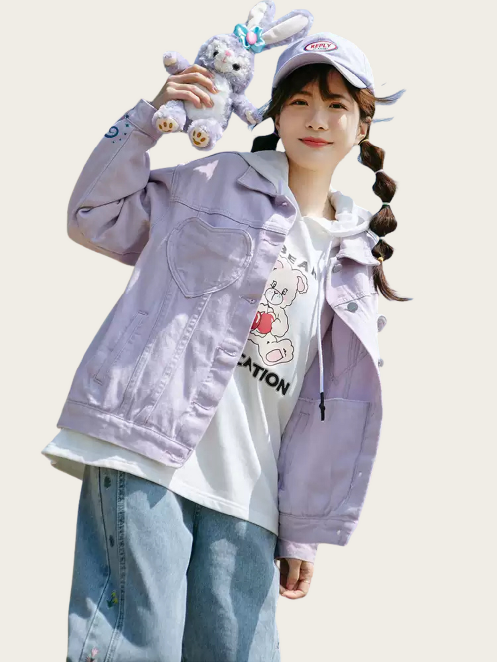 Person wearing a light purple jacket over a white hoodie with cartoon design, holding a plush toy, on a plain background.
