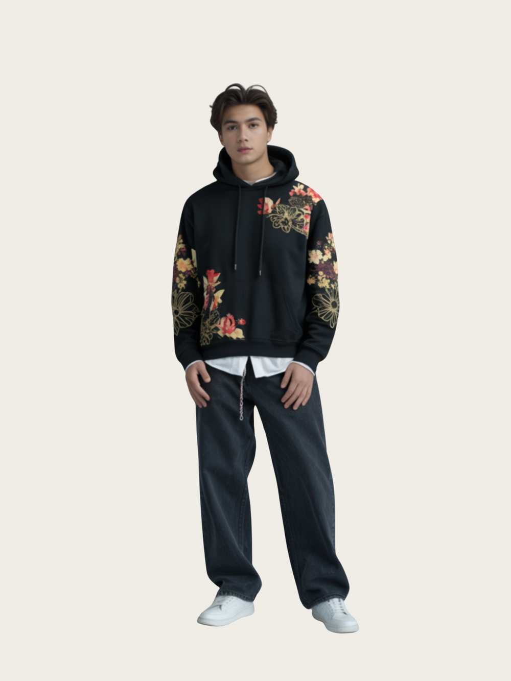 Person wearing a black hoodie with floral patterns on sleeves and dark pants against a light background