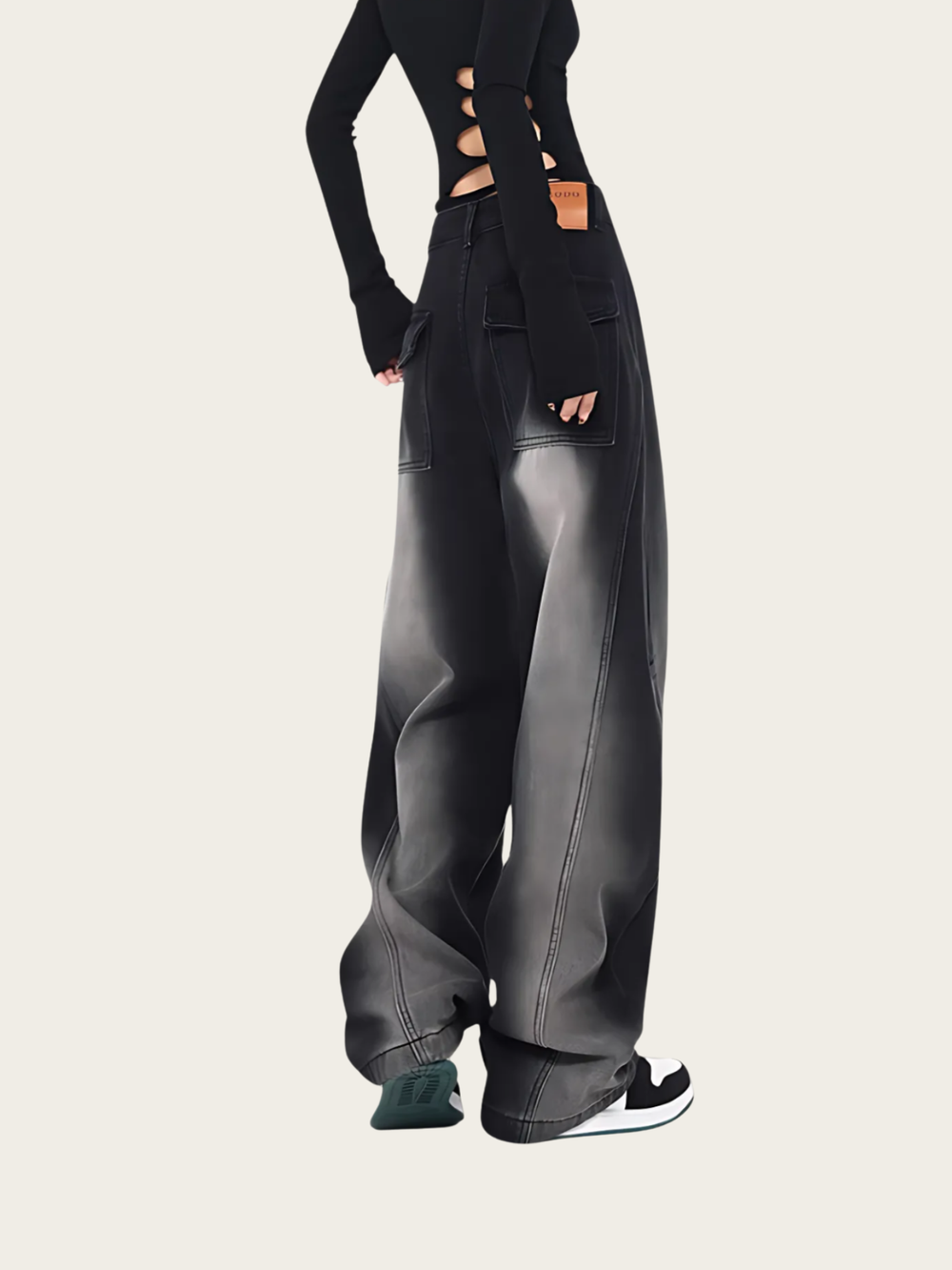 Person wearing black leather pants on a plain background