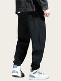 Person wearing black pants and white sneakers on a plain background