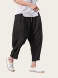 Person wearing black wide-leg pants with a white shirt on a light background
