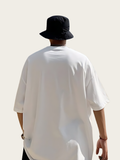 Person wearing a white oversized shirt and black bucket hat on a plain background