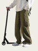 Person wearing green cargo pants with a scooter on a plain background