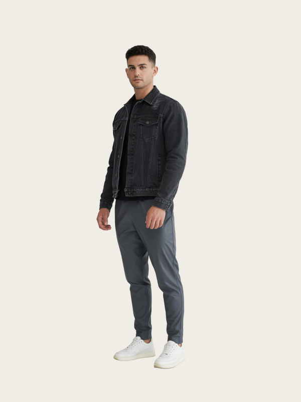 Man wearing a black denim jacket and gray pants on a white background