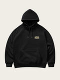 Black hoodie with a small logo on the chest against a light beige background