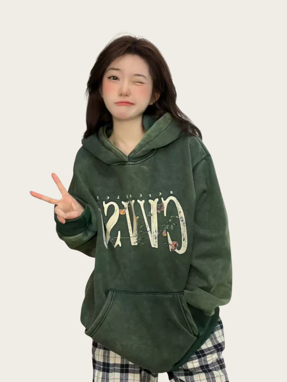 Person wearing a green hoodie with text and graphics on a plain background