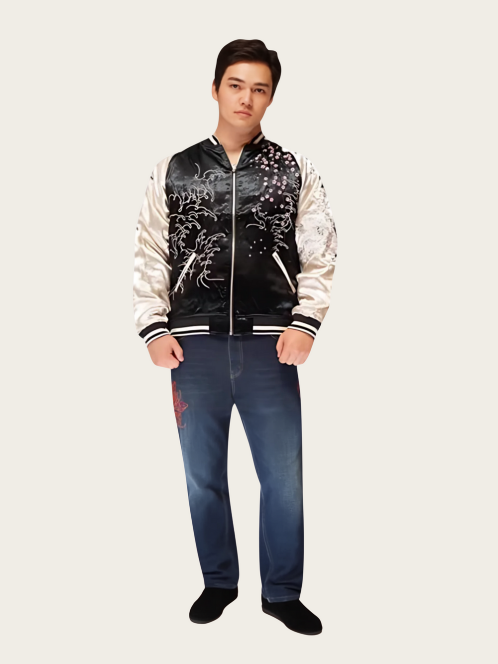 Person wearing a black and white varsity jacket with dragon designs and blue jeans on a white background