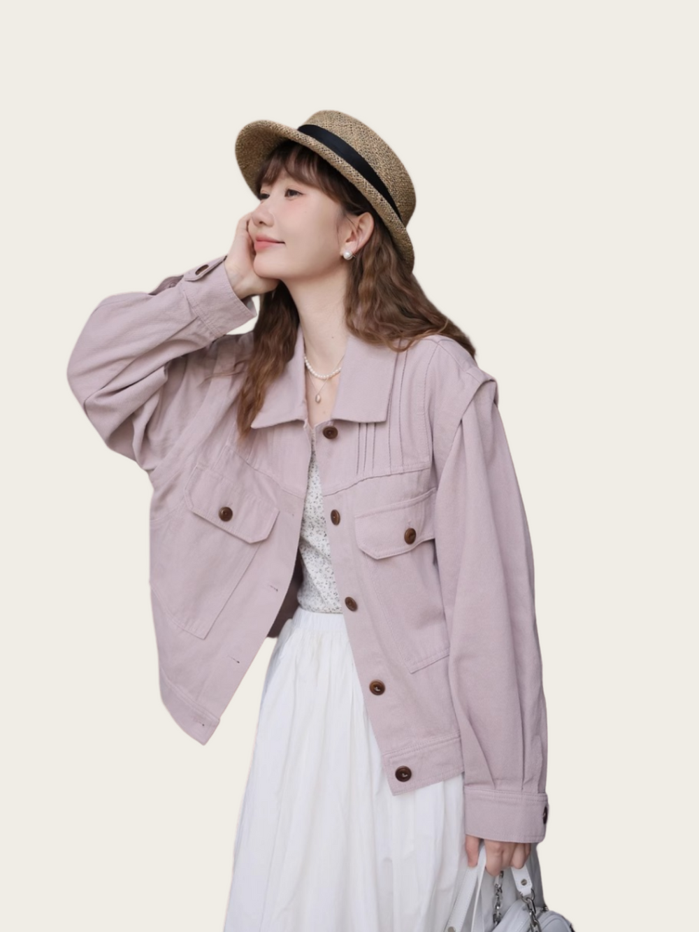 Woman wearing a light purple jacket and white dress with a straw hat on a beige background