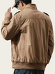 Person wearing a brown jacket and cap on a plain background