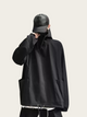 Person wearing a black jacket and cap on a light beige background