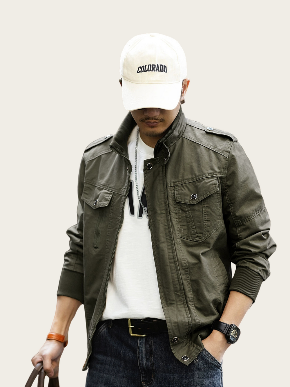 Person wearing a green jacket, white cap, and dark jeans on a plain background