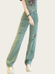 Person wearing light green distressed jeans on a plain background