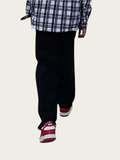 Person wearing black pants with red and white striped socks on a light background