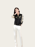 Woman wearing a black and white jacket with floral embroidery on a white background