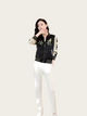 Woman wearing a black and white jacket with floral embroidery on a white background