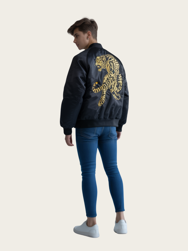 Person wearing a black bomber jacket with a gold tiger design on the back, standing against a white background.