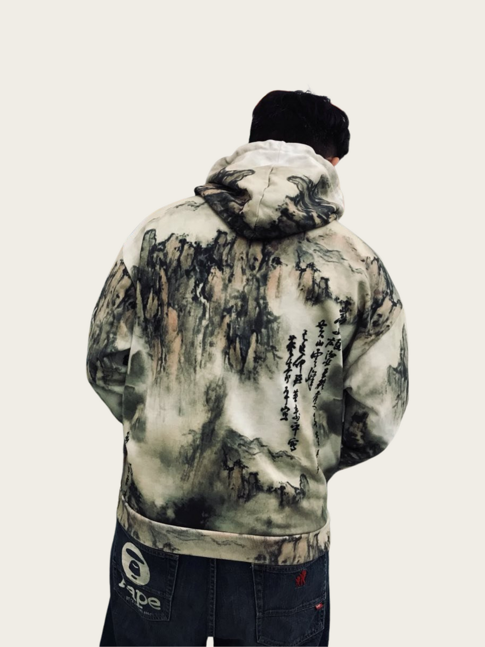 Person wearing a hoodie with artistic design on the back, standing against a plain background