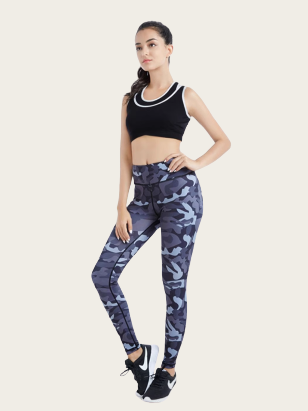 Woman wearing a black sports bra and blue camouflage leggings on a white background