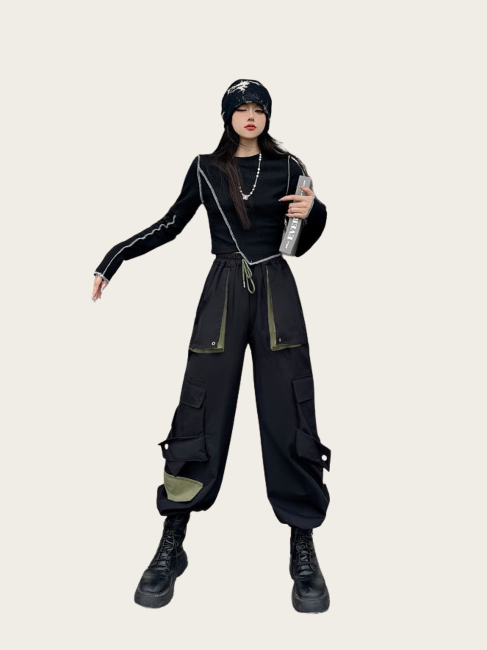 Person wearing a black outfit with cargo pants and a helmet on a beige background