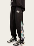 Black pants with colorful side panel and white sneakers on a white background