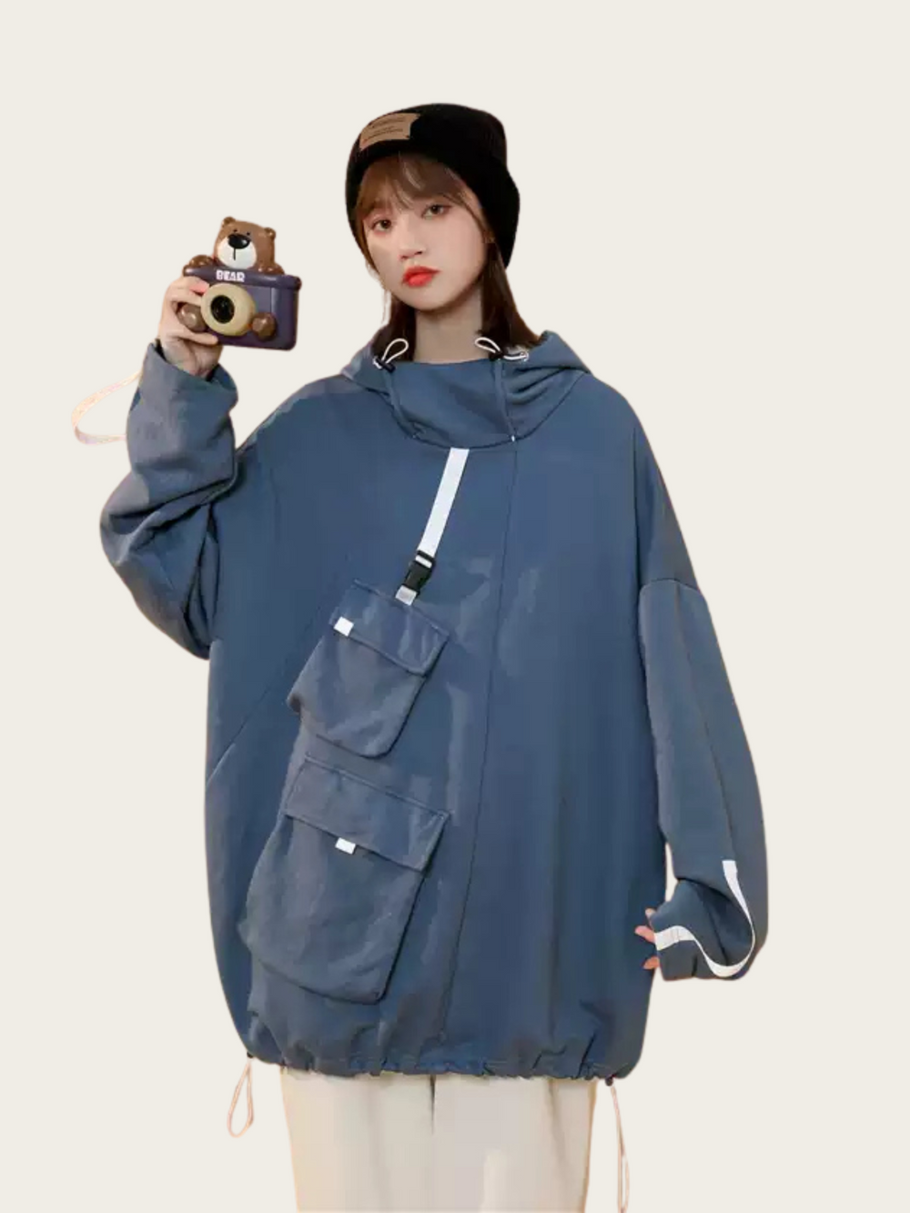 Person wearing a blue hooded jacket with a camera, on a plain background