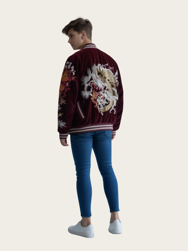 Person wearing a burgundy bomber jacket with floral embroidery on a plain background