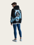 Person wearing a black hoodie with blue graphic design on the back, standing against a white background