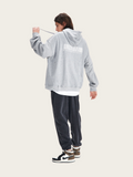 Person wearing a gray hoodie with text on the back, standing against a white background