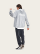 Person wearing a gray hoodie with text on the back, standing against a white background