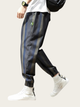 Person wearing black and gray striped pants with white sneakers on a light background