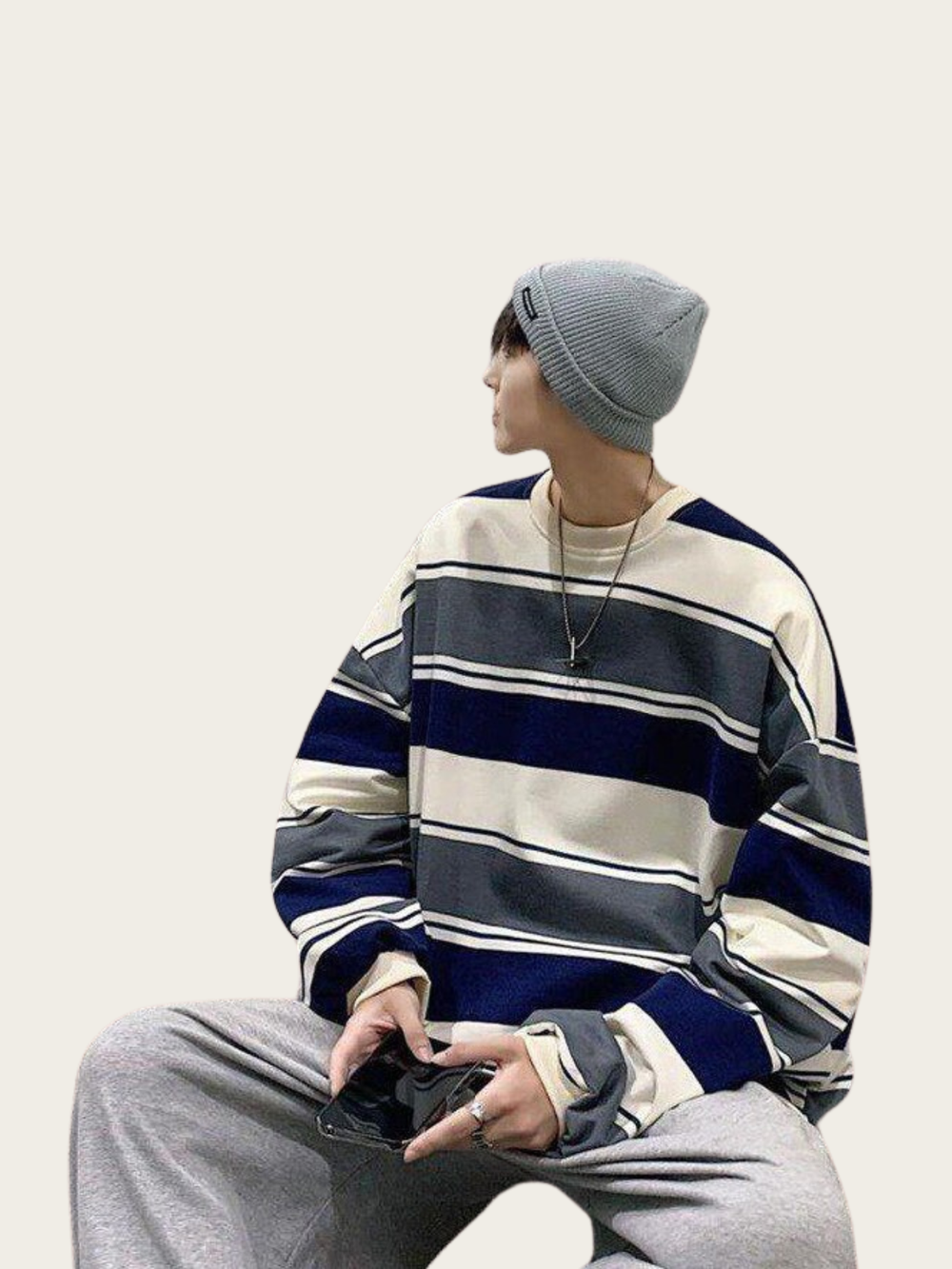 Person wearing a striped sweater and gray beanie sitting on a white background