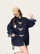 Person wearing a navy blue denim jacket and beige cap on a light background