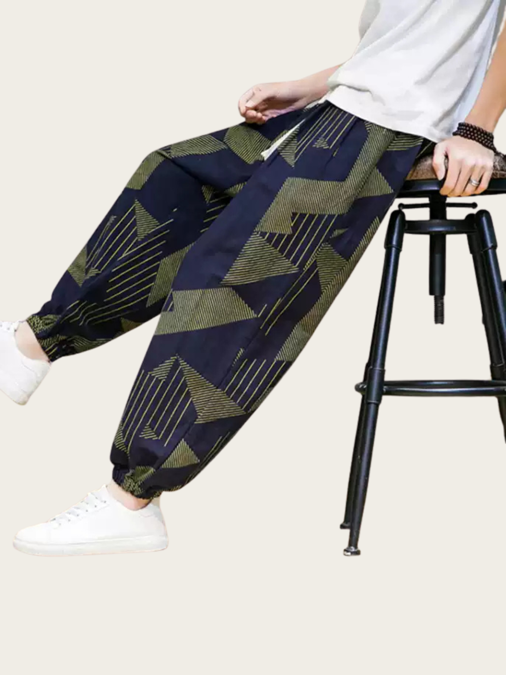 Person wearing patterned pants sitting on a stool with a neutral background