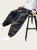 Person wearing patterned pants sitting on a stool with a neutral background