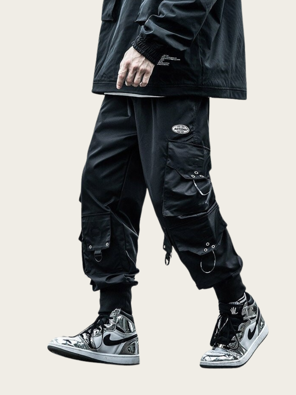 Person wearing black cargo pants and high-top sneakers on a beige background
