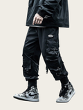 Person wearing black cargo pants and high-top sneakers on a beige background