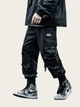Person wearing black cargo pants and high-top sneakers on a beige background
