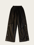 Black cargo pants with button details on a light gray background