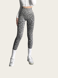 Person wearing gray leopard print leggings on a beige background