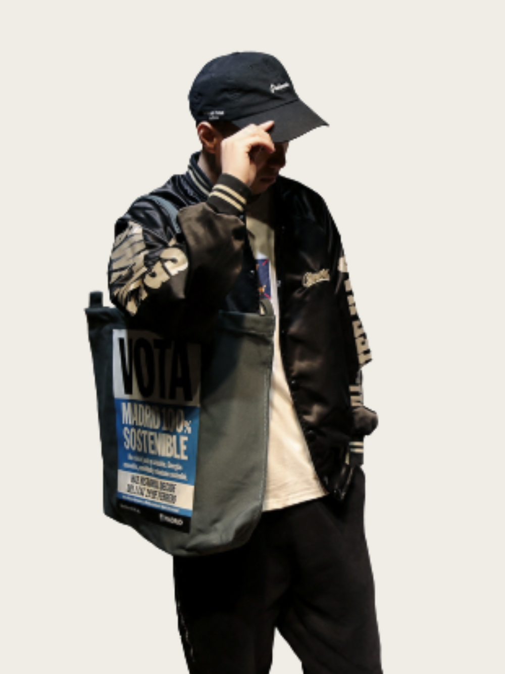 Person wearing a black jacket with branding, holding a black bag with visible text.
