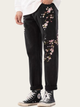 Black pants with floral embroidery worn by a person on a white background