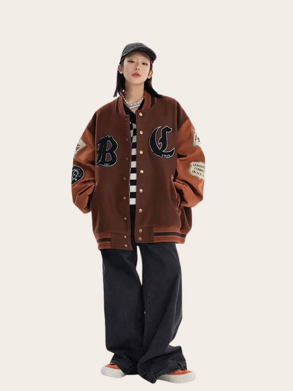 Person wearing a brown varsity jacket with lettering on a white background