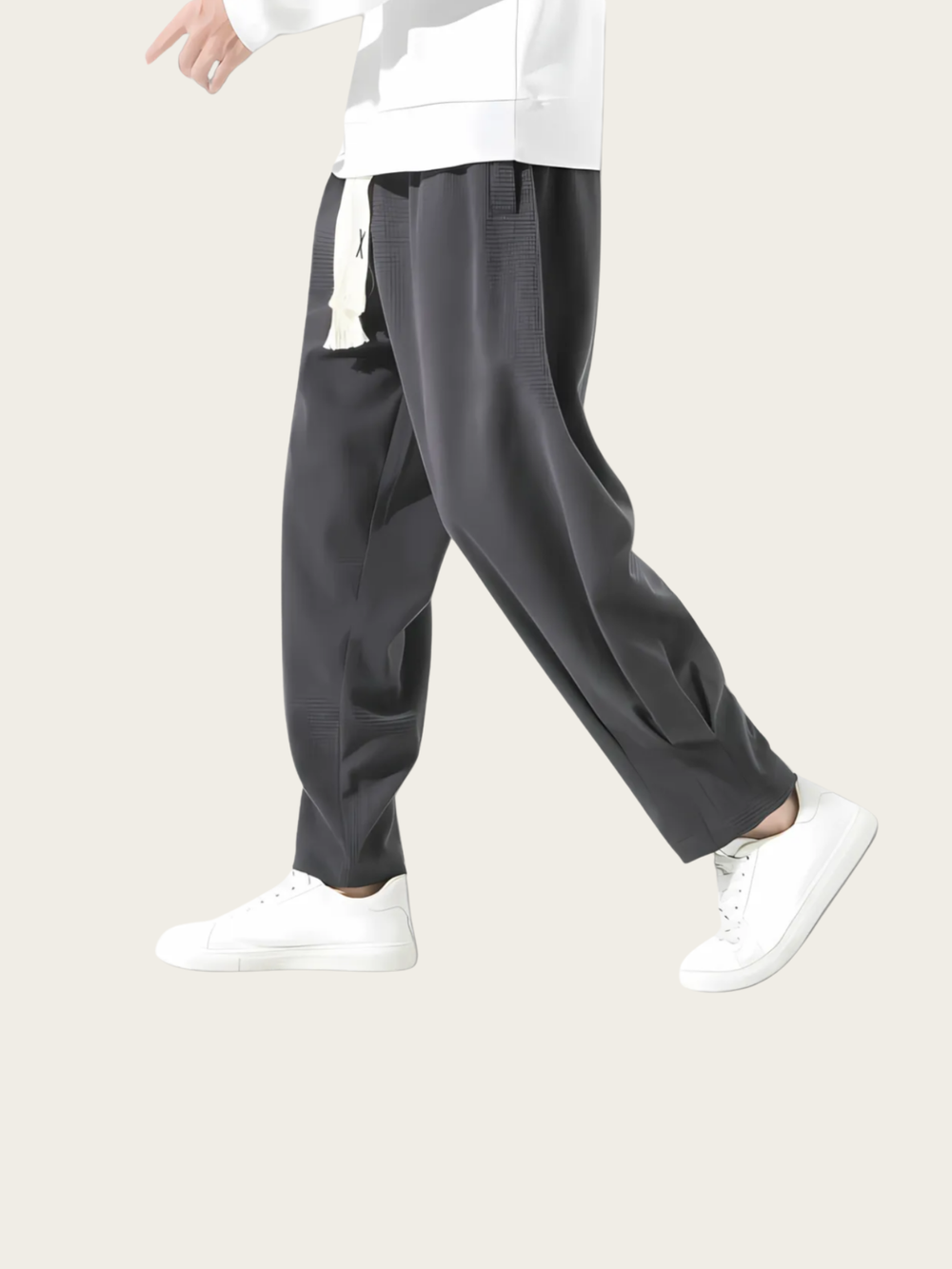 Person wearing dark gray wide-leg pants and white sneakers on a light beige background