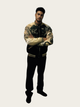 Person wearing a camouflage-patterned varsity jacket on a white background